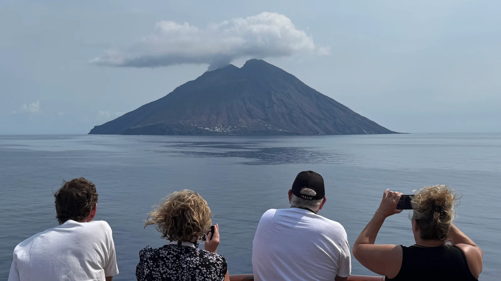 Four people looking out at Mount Stromboli from a cruise ship